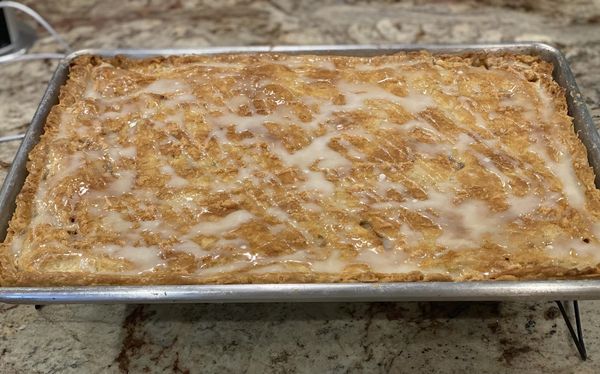 Golden-brown apple slab pie with a flaky crust and powdered sugar glaze, fresh out of the oven