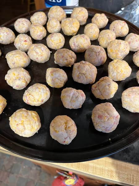 Raw sausage balls on a cast iron pan, ready to be baked for an easy three-ingredient appetizer