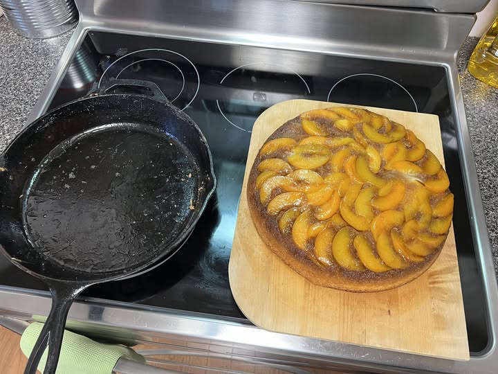 Easy peach upside down cake with caramelized peaches and golden crust, served on a plate with whipped cream.