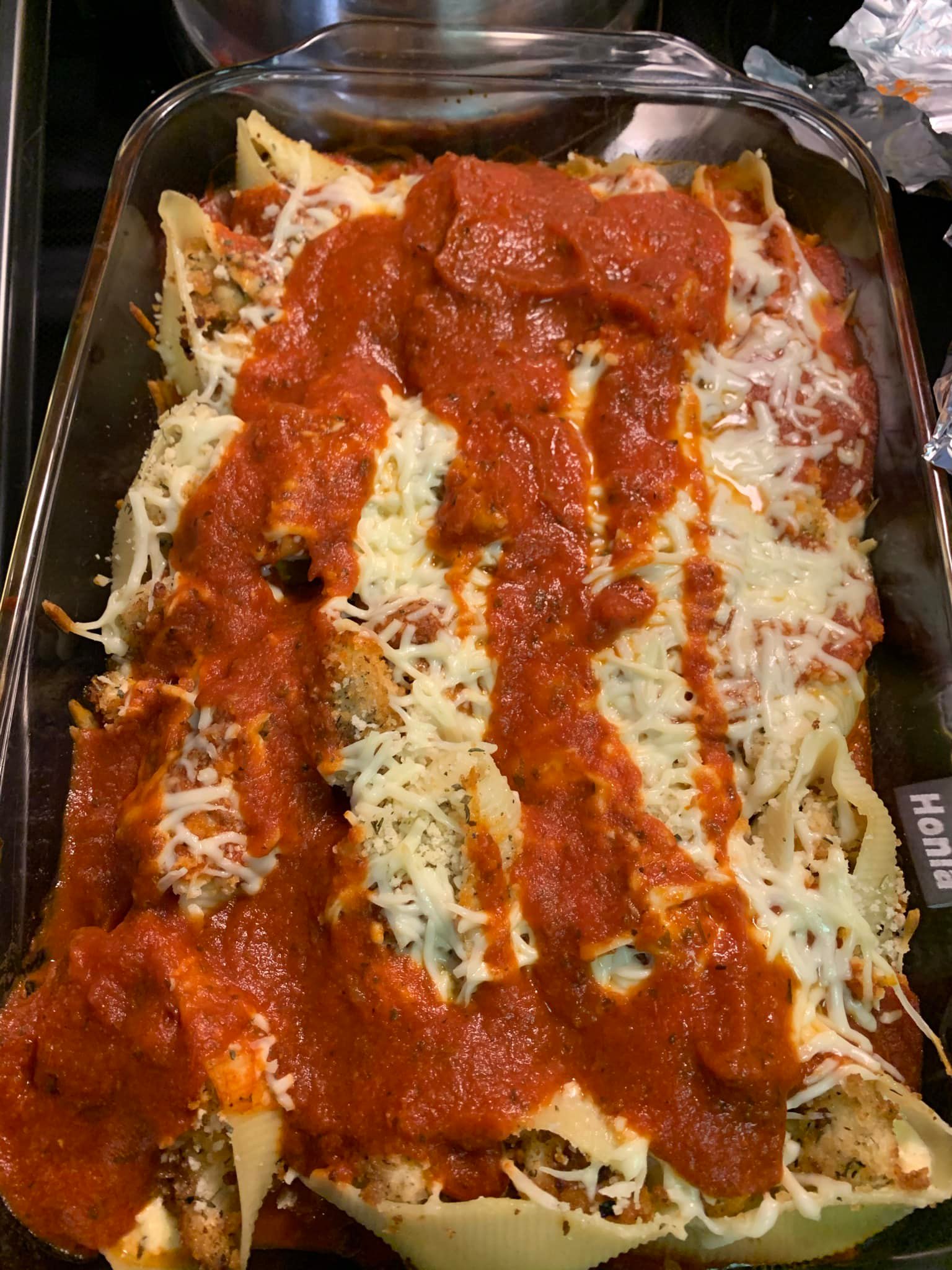 A bubbling hot dish of Chicken Parmesan Stuffed Shells fresh out of the oven, covered in melted mozzarella and marinara sauce.