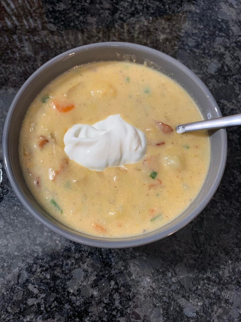 A bowl of creamy Loaded Baked Potato Soup topped with crispy bacon, chopped chives, and a dollop of sour cream.