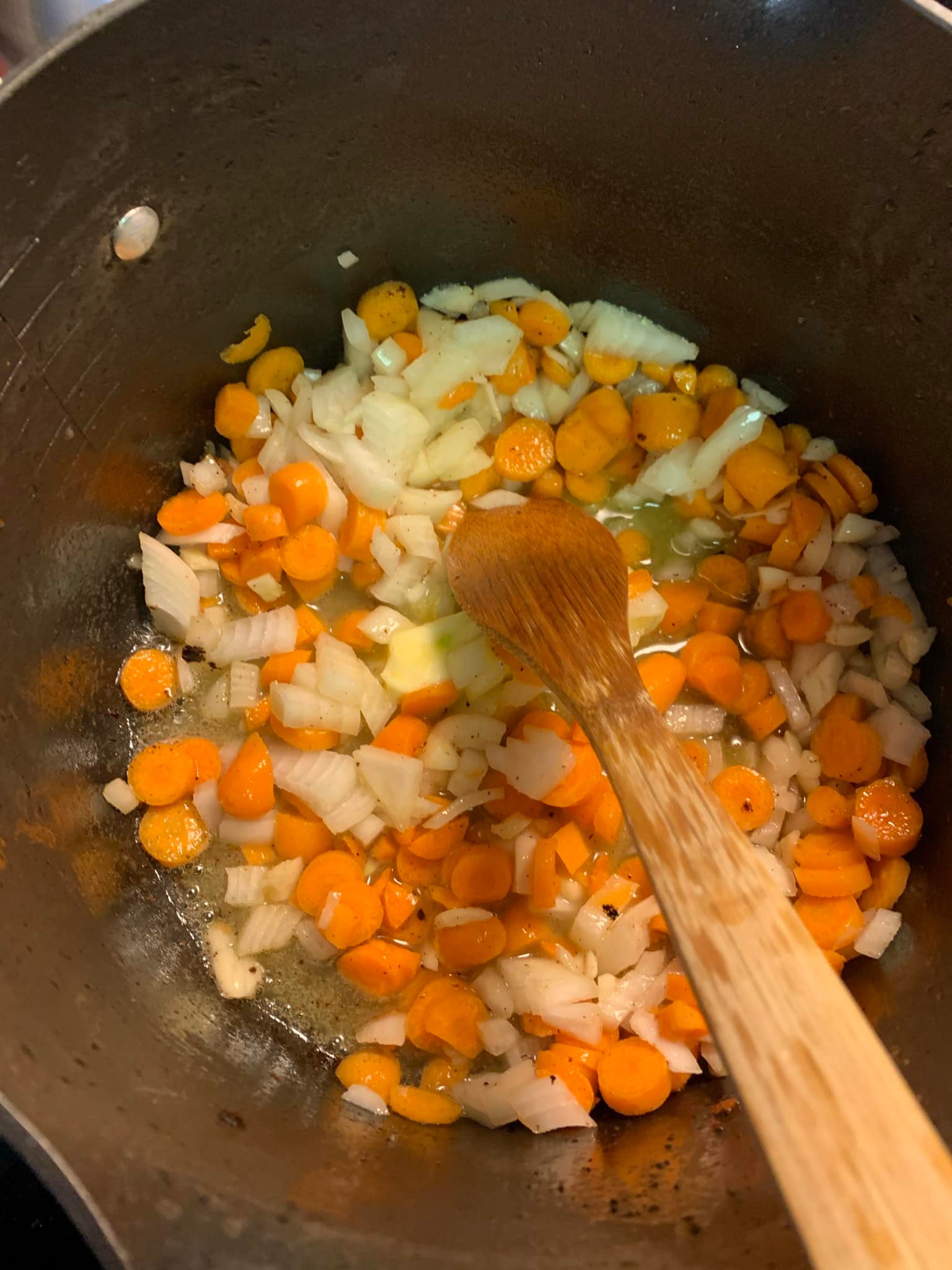 A handful of fresh chives being chopped and added to a simmering pot of potato soup.