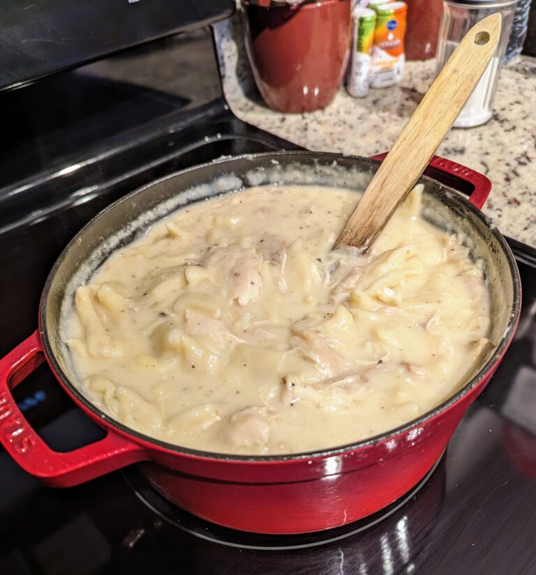 A pot of homemade chicken and dumplings simmering on the stove, with a creamy broth and tender dumplings.