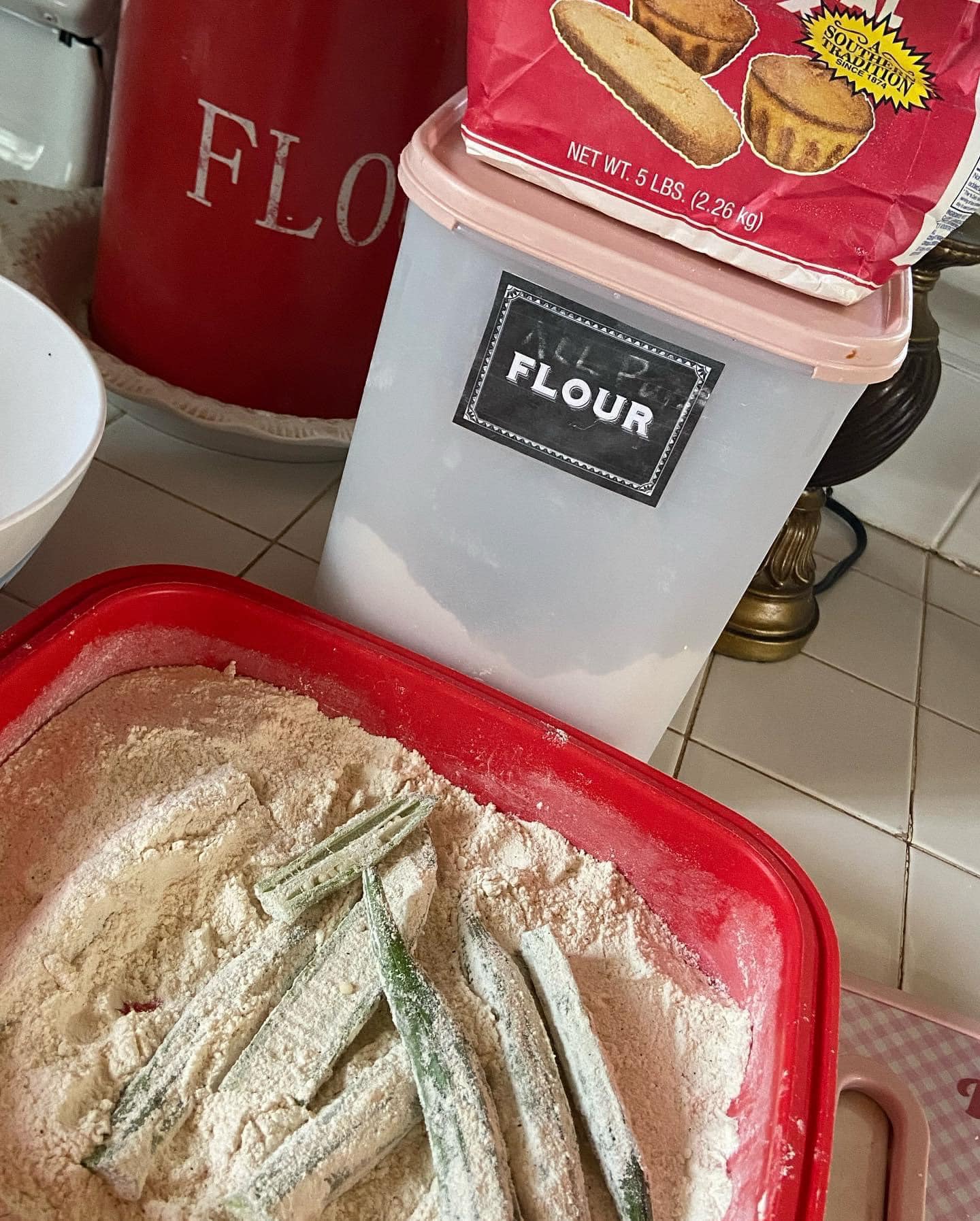 A seasoned flour and cornmeal mixture in a red container, ready for coating the okra.