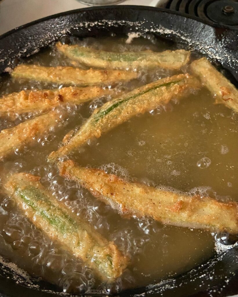 Okra pieces frying in hot oil, creating a crispy, golden crust.