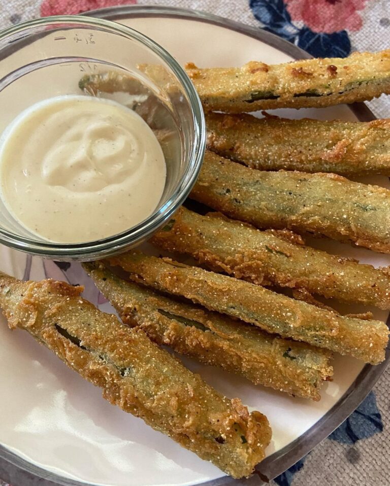 Perfectly fried okra served on a plate with dipping sauce.