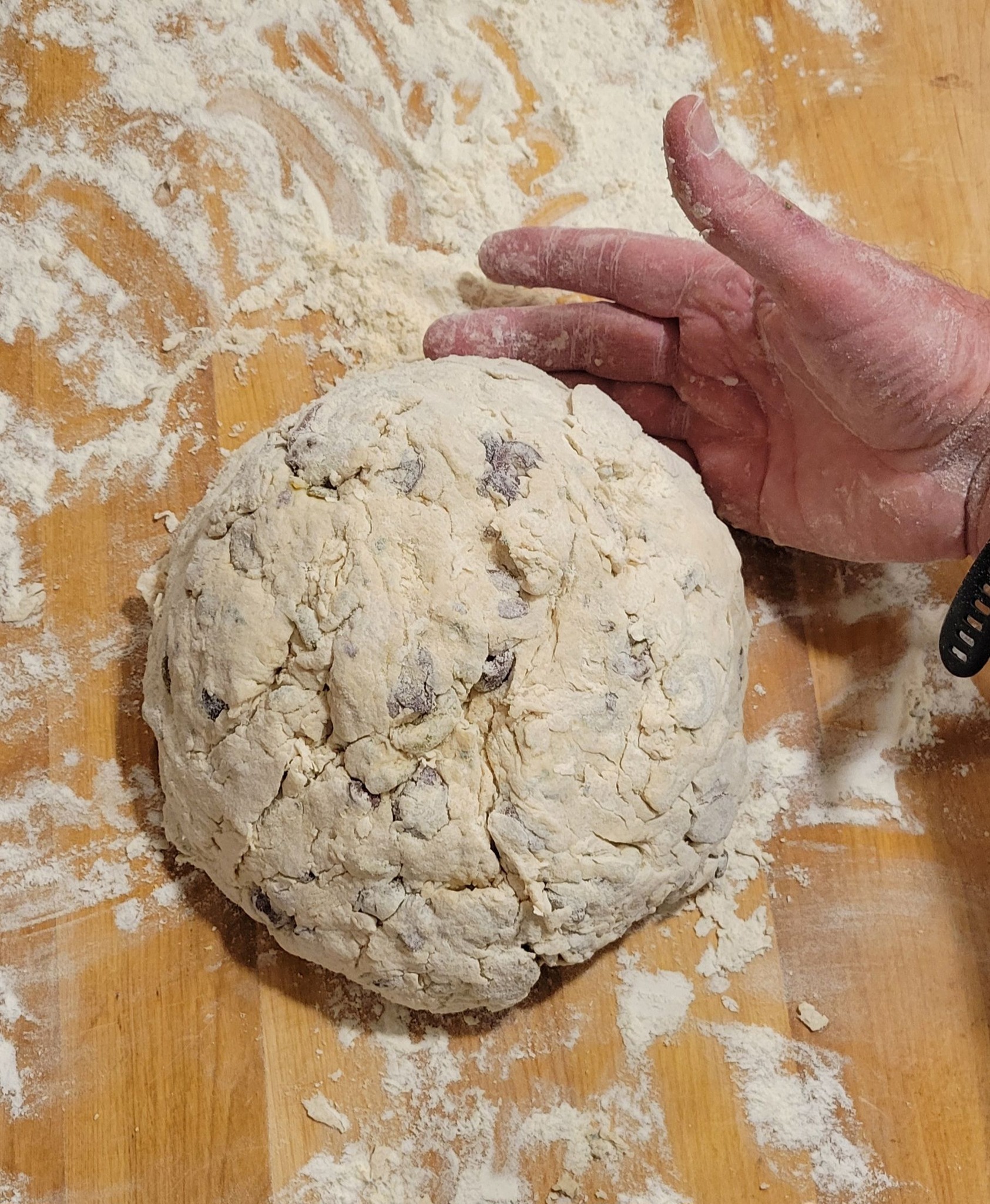 A round dough ball on a floured wooden surface, ready to rise.