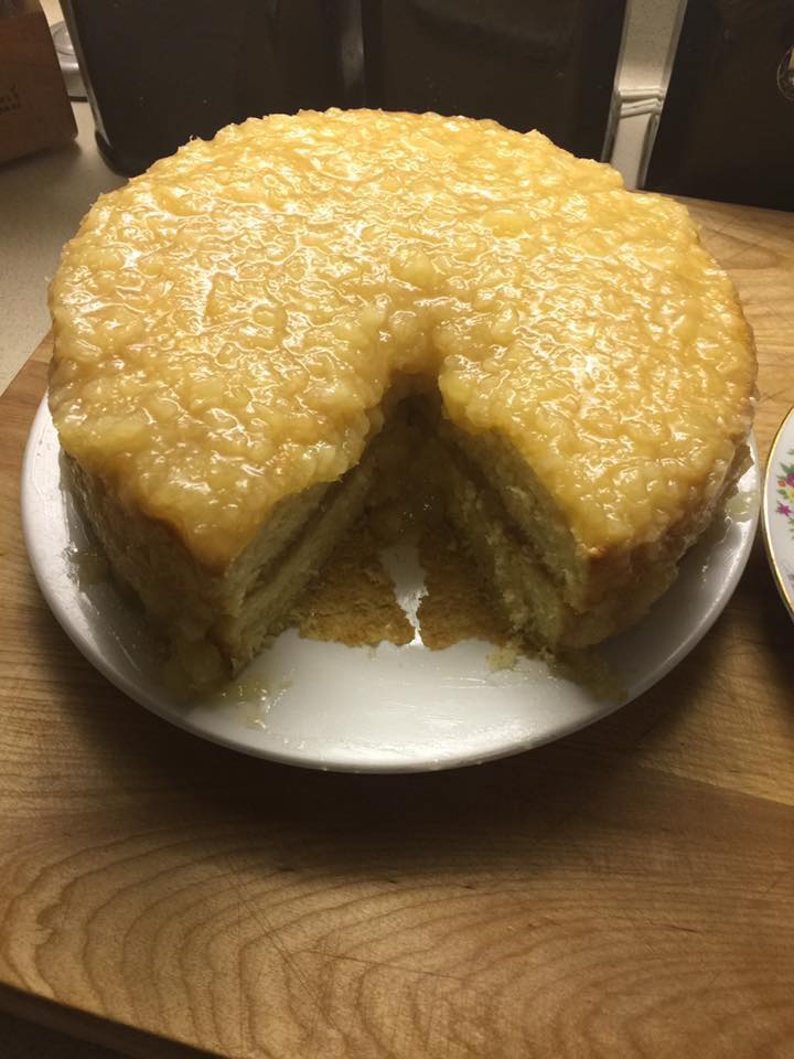 A slice of pineapple cake with golden glaze, served on a floral plate.