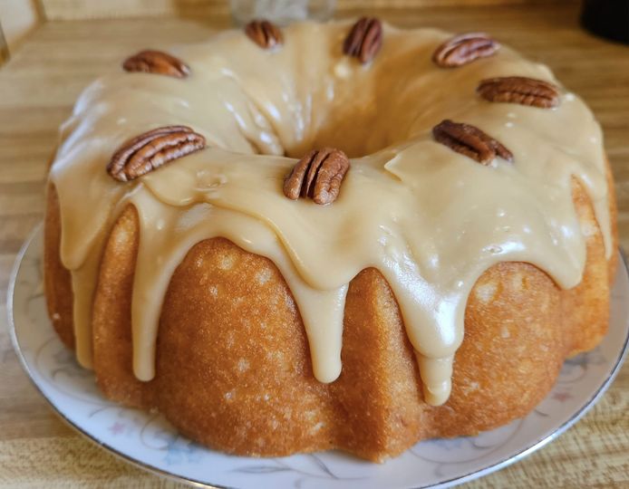 A golden Kentucky Bourbon Butter Cake drizzled with salted caramel glaze and garnished with pecans.