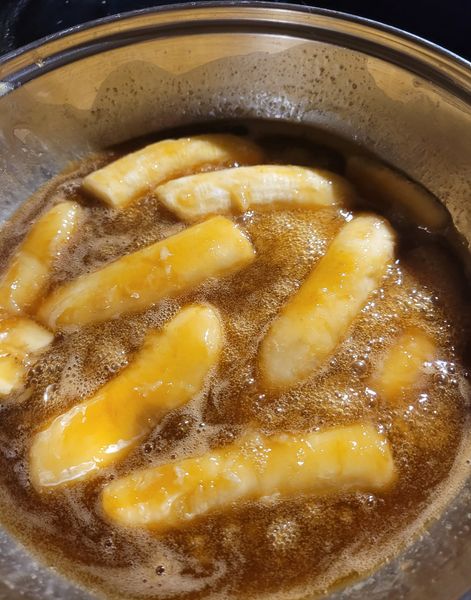 Sliced bananas simmering in a rich rum and brown sugar sauce.