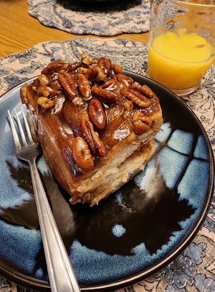 A tray of caramel rolls being pulled apart, revealing their soft and fluffy layers.
