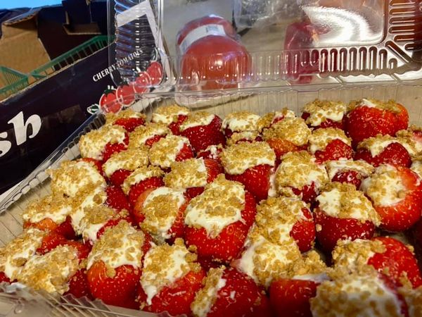 A tray of cheesecake stuffed strawberries topped with graham cracker crumble, ready to be served.