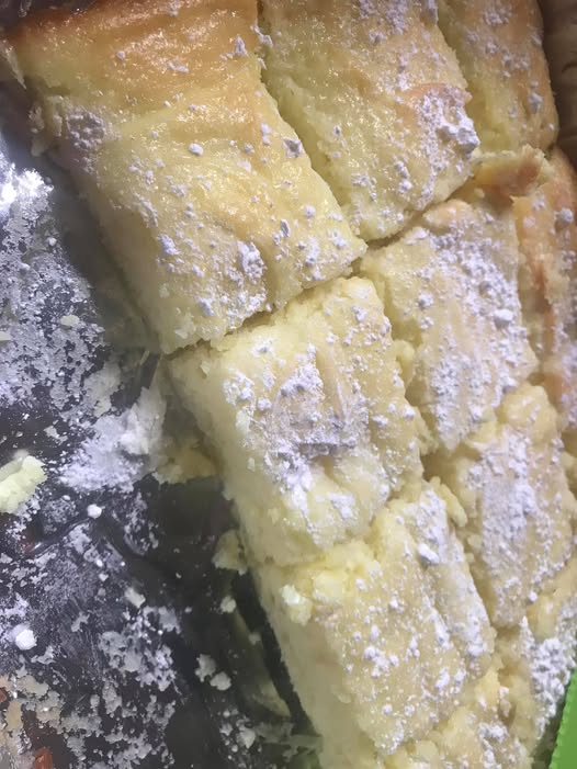 A close-up of lemon bars cut into squares, dusted with powdered sugar, and ready to serve.
