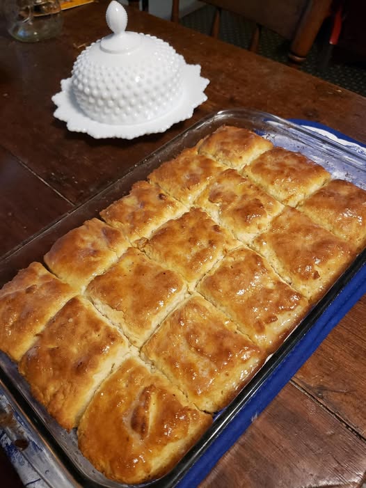 A glass baking dish filled with golden, fluffy 7-Up biscuits, brushed with melted butter.