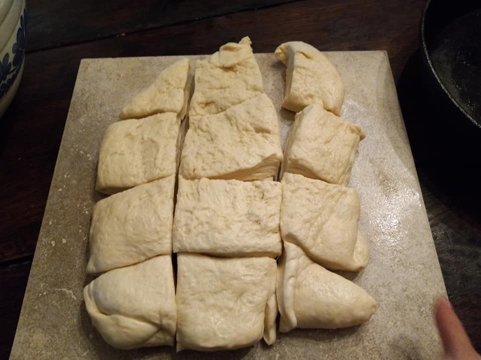 Homemade roll dough cut into portions, ready to be shaped.