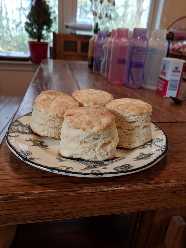 Freshly baked homemade biscuits on a decorative plate, showing their golden brown flaky layers."