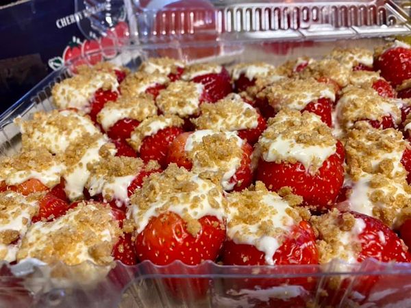 A tray of cheesecake stuffed strawberries topped with graham cracker crumble, ready to be served.