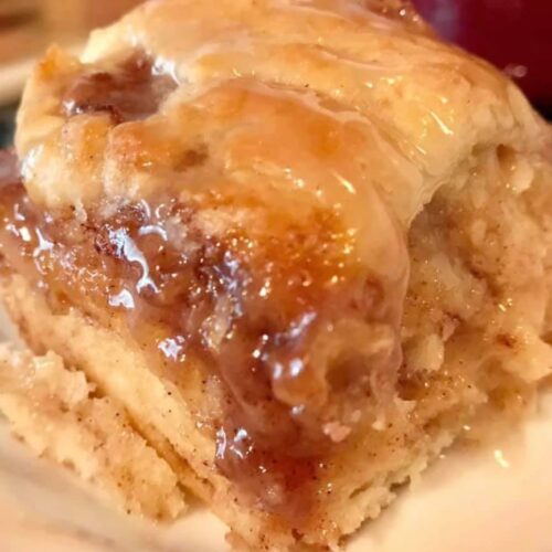 Close-up of cinnamon roll biscuit showing flaky layers and vanilla glaze.