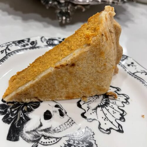 Slice of pumpkin pie with a golden, flaky crust served on a black-and-white vintage skull plate. Great for showcasing a well-baked bottom crust