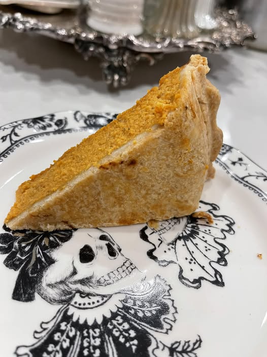 Slice of pumpkin pie with a golden, flaky crust served on a black-and-white vintage skull plate. Great for showcasing a well-baked bottom crust