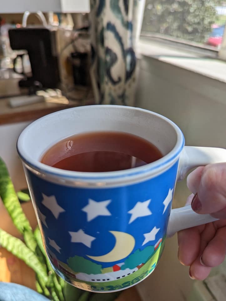 A mug of homemade sassafras tea with rich reddish-brown color on a rustic wooden table