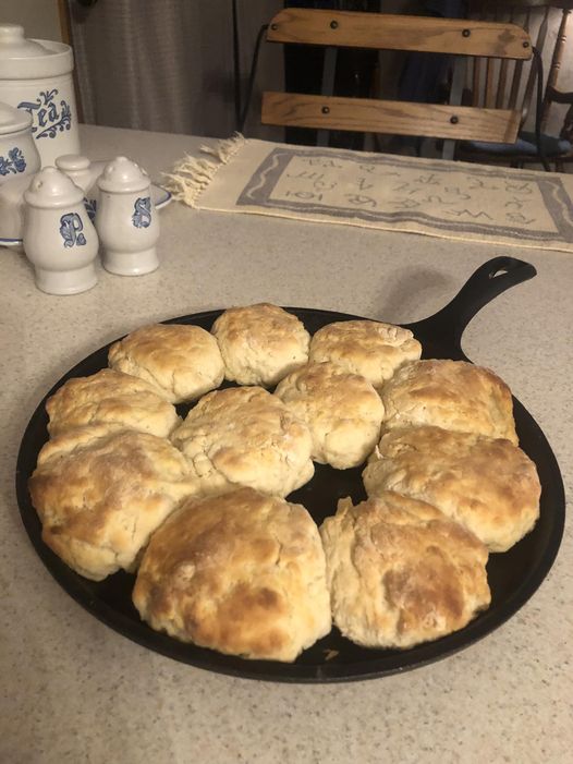 Homemade buttermilk biscuits baked in a cast iron griddle, arranged in a circle and golden brown.