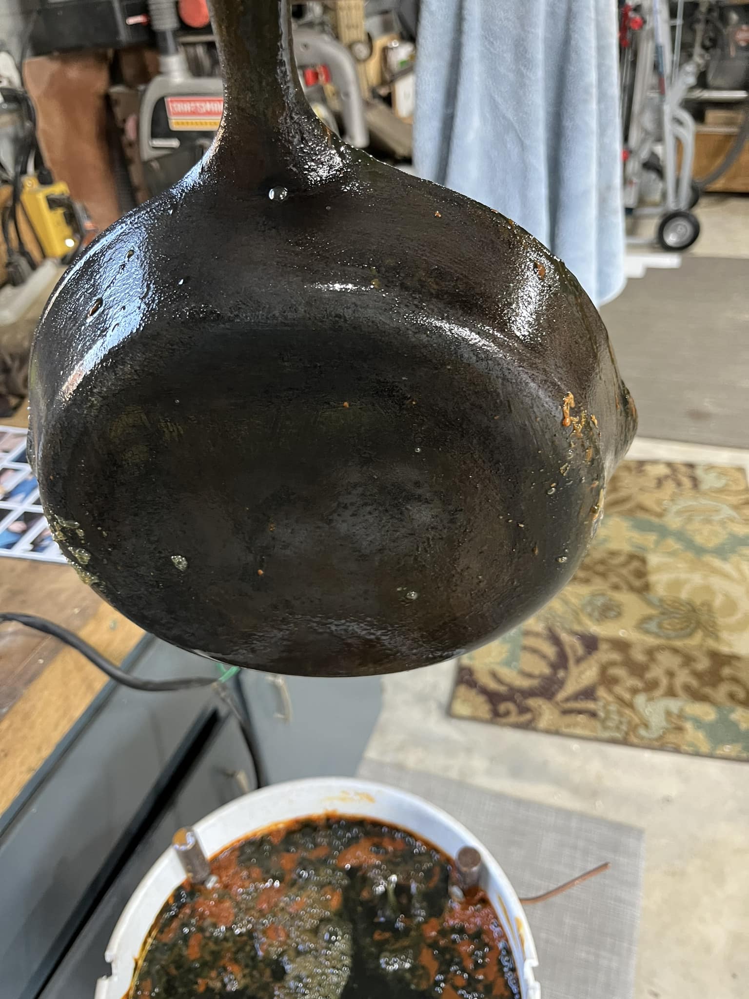 Cast iron skillet lifted from electrolysis bath, mostly clean