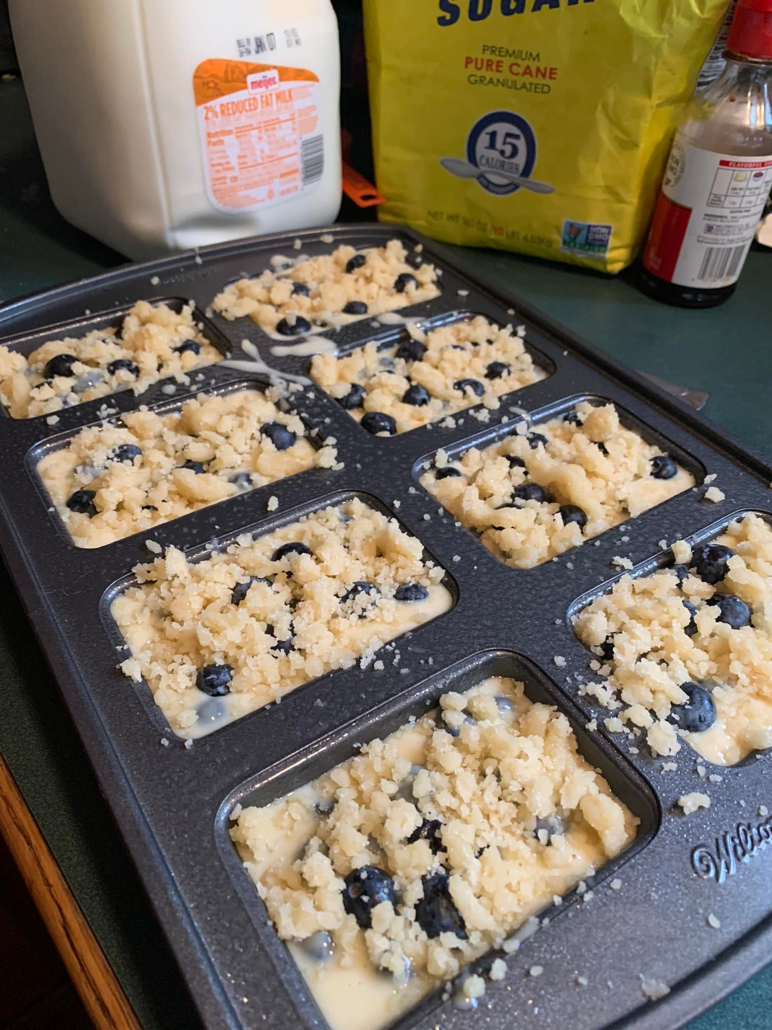 Fresh blueberry muffin batter topped with crumb streusel in a loaf pan, ready for baking.