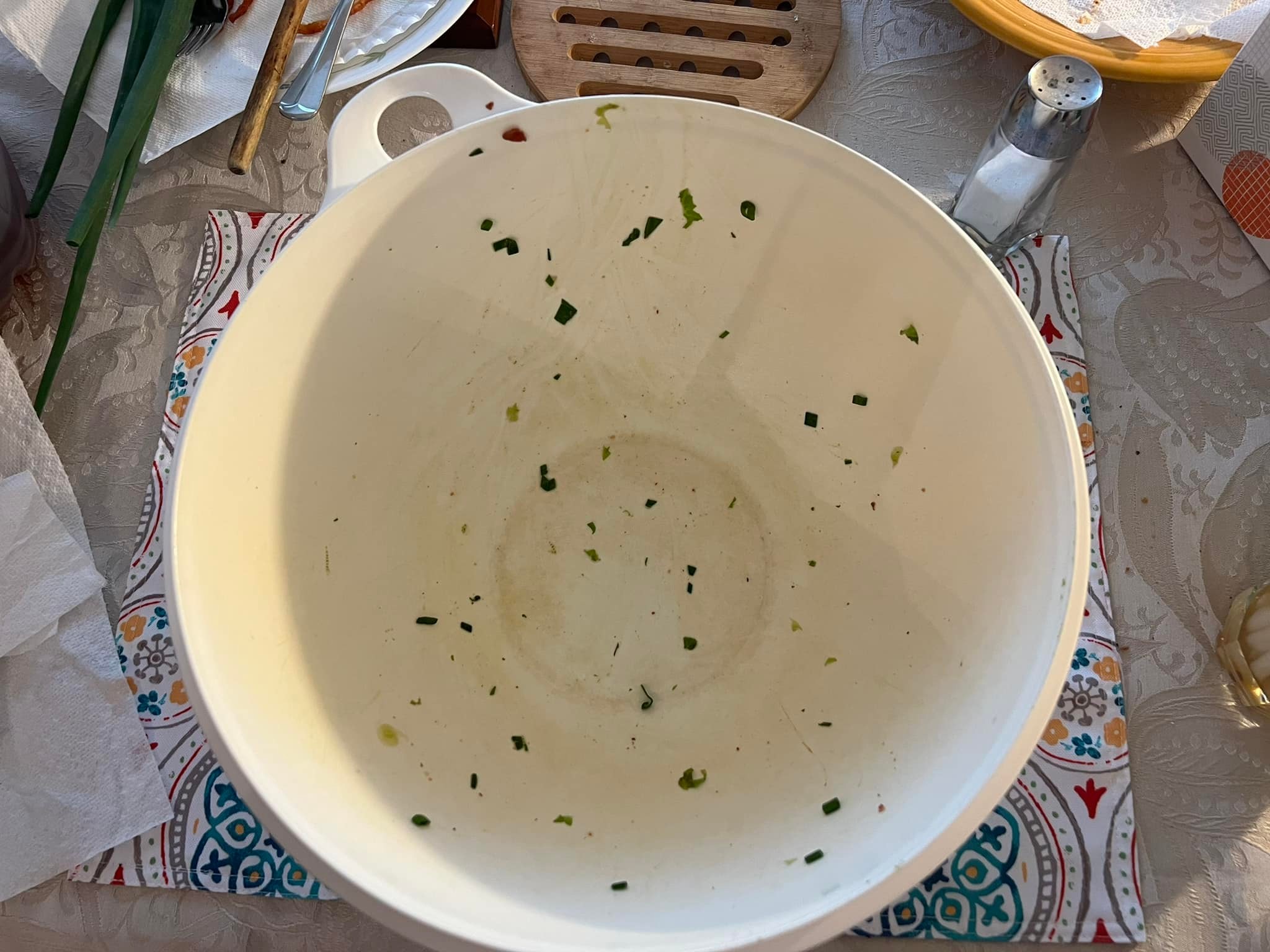 Empty white salad bowl with leftover green onion bits.