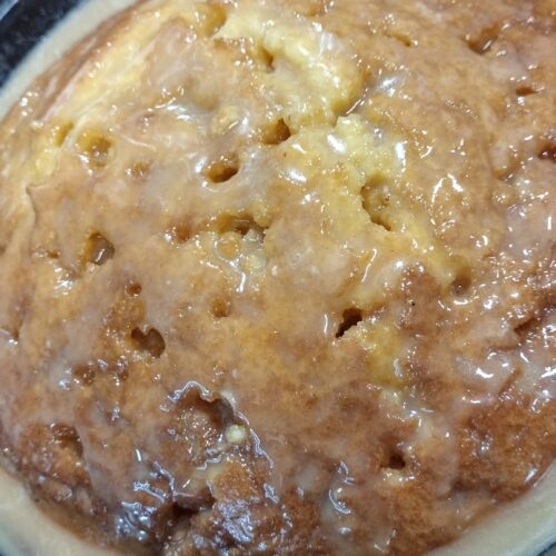 Poked holes in cake with glaze being prepared.