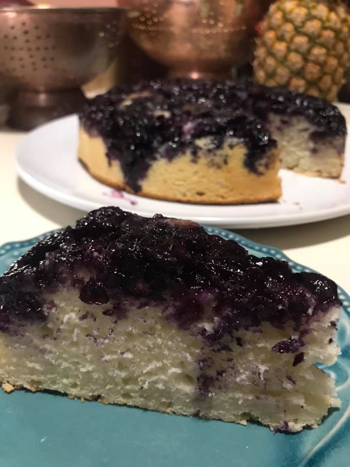 A slice of blueberry upside-down cake showing caramelized berry topping and fluffy vanilla crumb