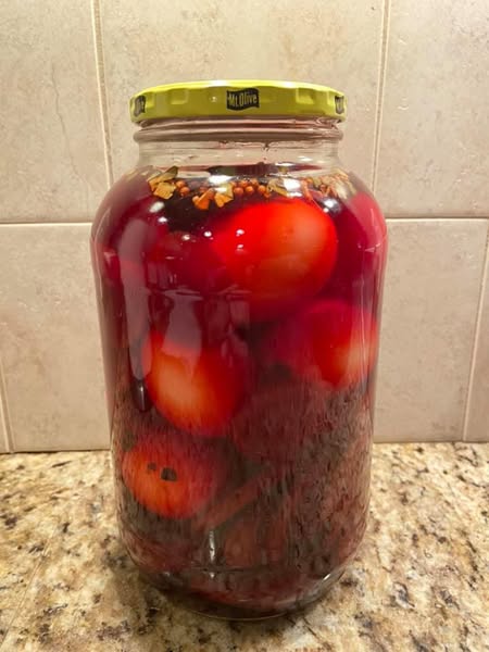 Sealed jar of pickled eggs and beets on a countertop, ready to refrigerate.
