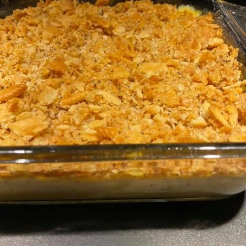 Baked poppy seed chicken casserole in a glass dish with golden Ritz cracker topping, ready to serve