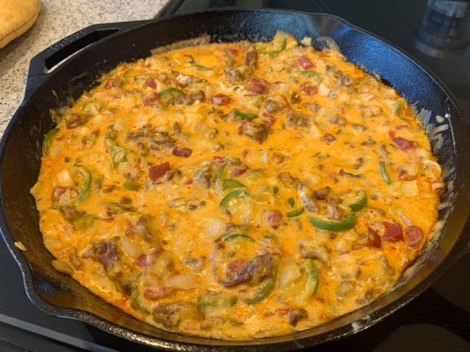 Fully melted and blended smoked queso dip in cast iron, ready to serve with chips.