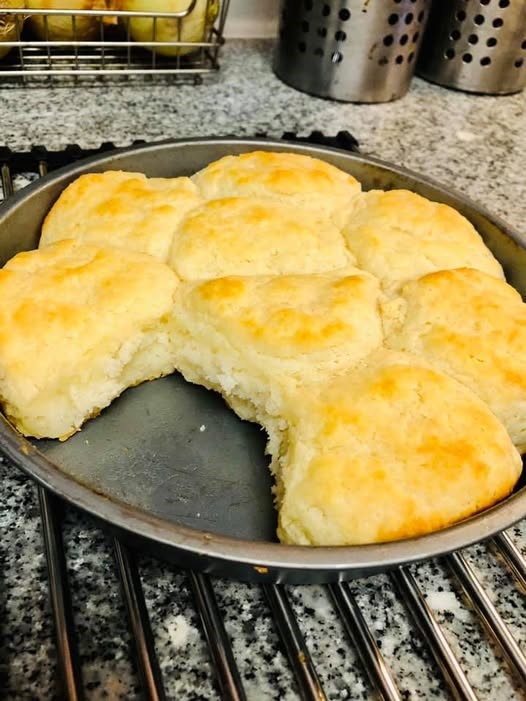 Fluffy homemade biscuits made with White Lily flour, baked golden in a round pan with one biscuit missing.