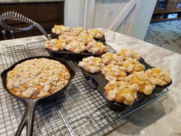 Pumpkin crumb muffins baked in vintage cast iron pans, topped with golden streusel and maple icing, cooling on a wire rack for a cozy fall breakfast