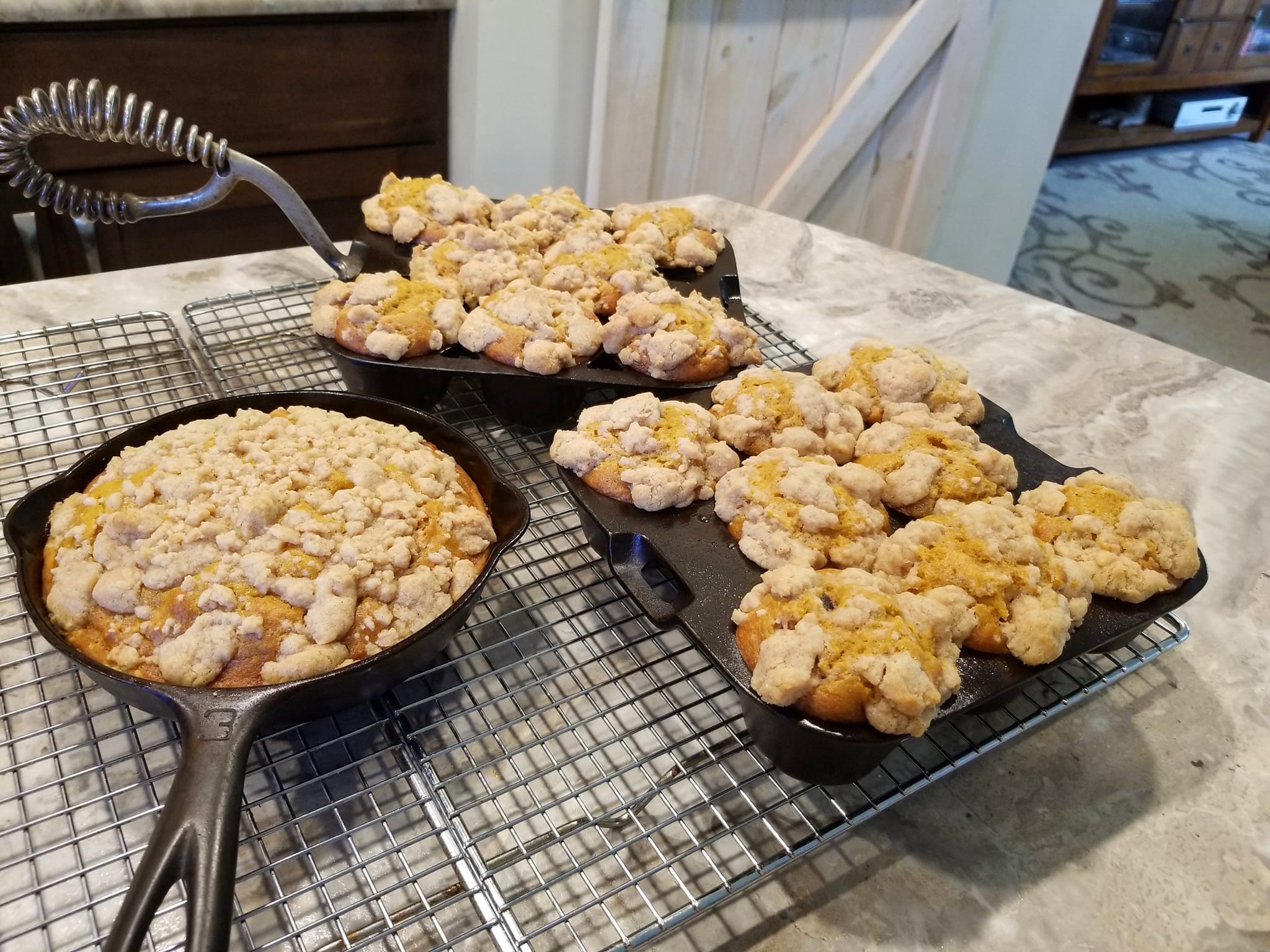 Pumpkin crumb muffins baked in vintage cast iron pans, topped with golden streusel and maple icing, cooling on a wire rack for a cozy fall breakfast