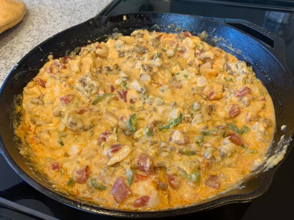 Smoked queso halfway through cooking, cheese starting to melt in a cast iron skillet on smoker.