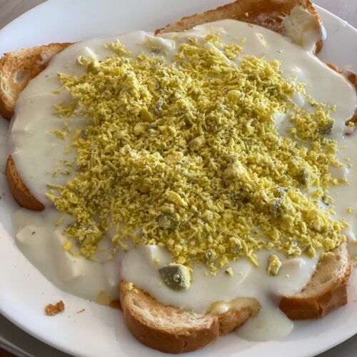 Close-up of eggs à la goldenrod with creamy white sauce and finely grated egg yolk on thick toast