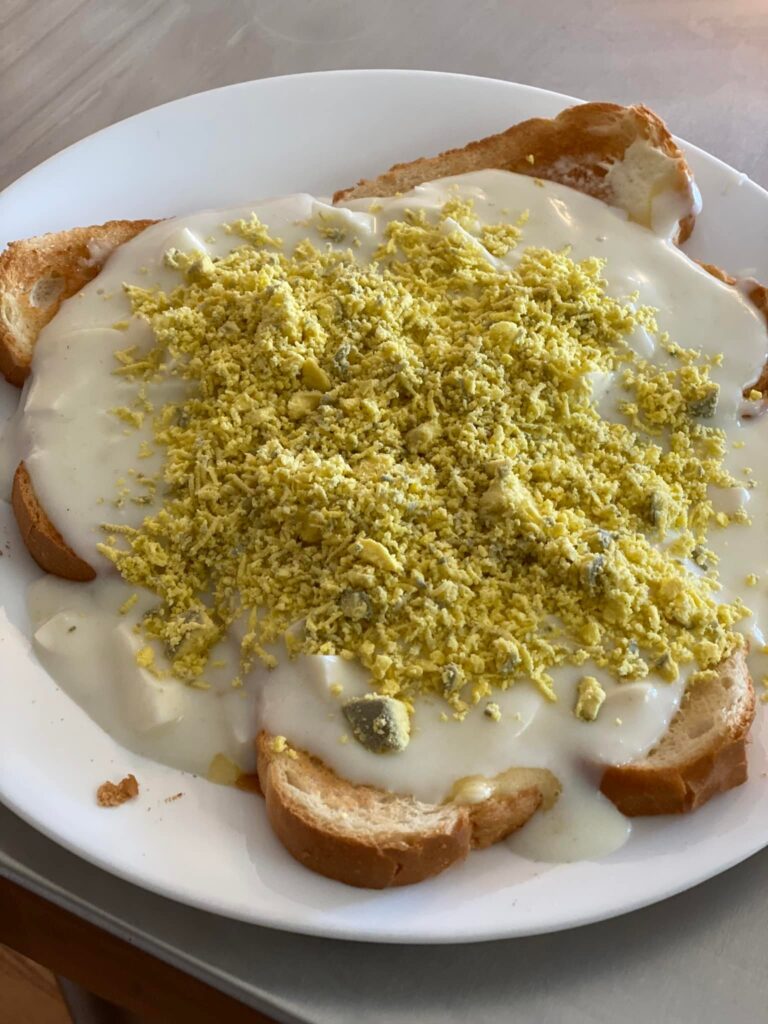 Close-up of eggs à la goldenrod with creamy white sauce and finely grated egg yolk on thick toast