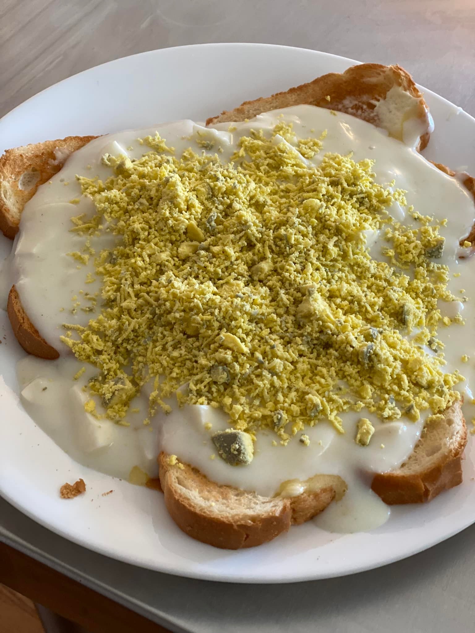 Close-up of eggs à la goldenrod with creamy white sauce and finely grated egg yolk on thick toast