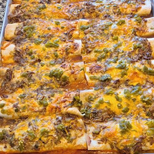 Baking dish filled with green chile pork enchiladas ready to serve.