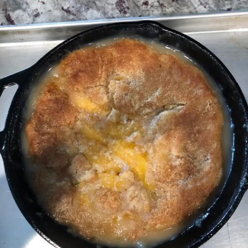 Golden cast‑iron skillet peach cobbler fresh from the oven