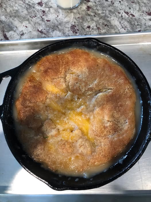 Golden cast‑iron skillet peach cobbler fresh from the oven