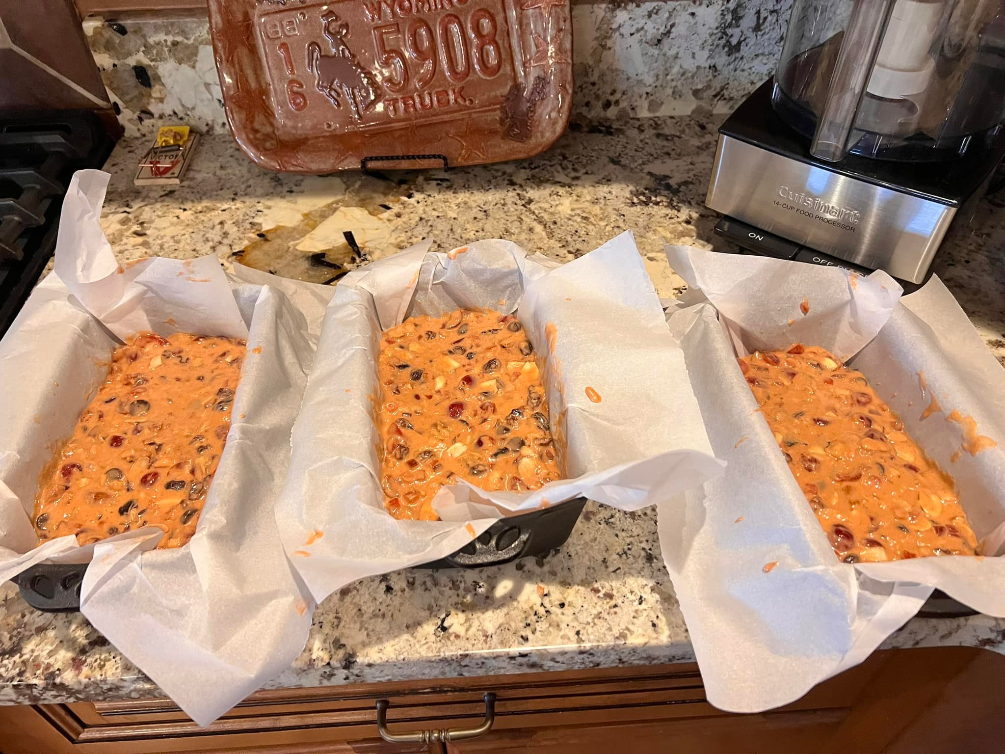Homemade fruitcake batter in parchment-lined cast iron loaf pans, ready for baking