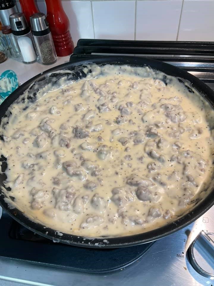 Creamy sausage gravy with evaporated milk simmering in cast‑iron skillet.