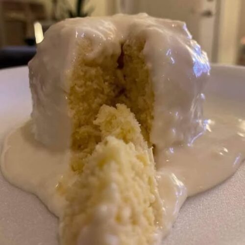 moist lemon mug cake in a white mug with glaze drizzle)