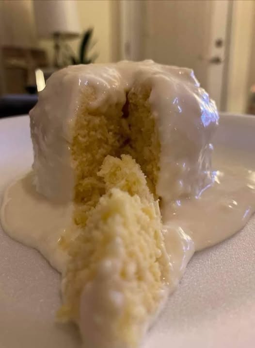 moist lemon mug cake in a white mug with glaze drizzle)