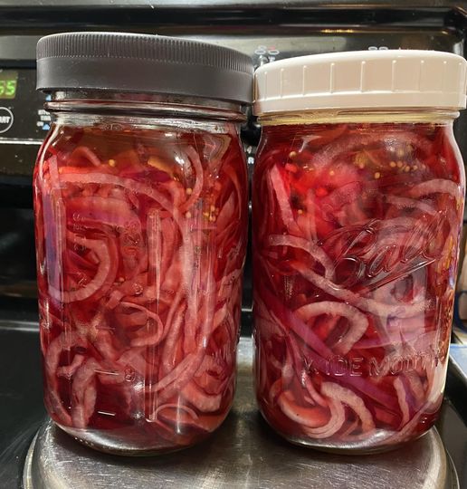 Vibrant quick pickled red onions packed tightly in a mason jar, layered with beet ribbons
