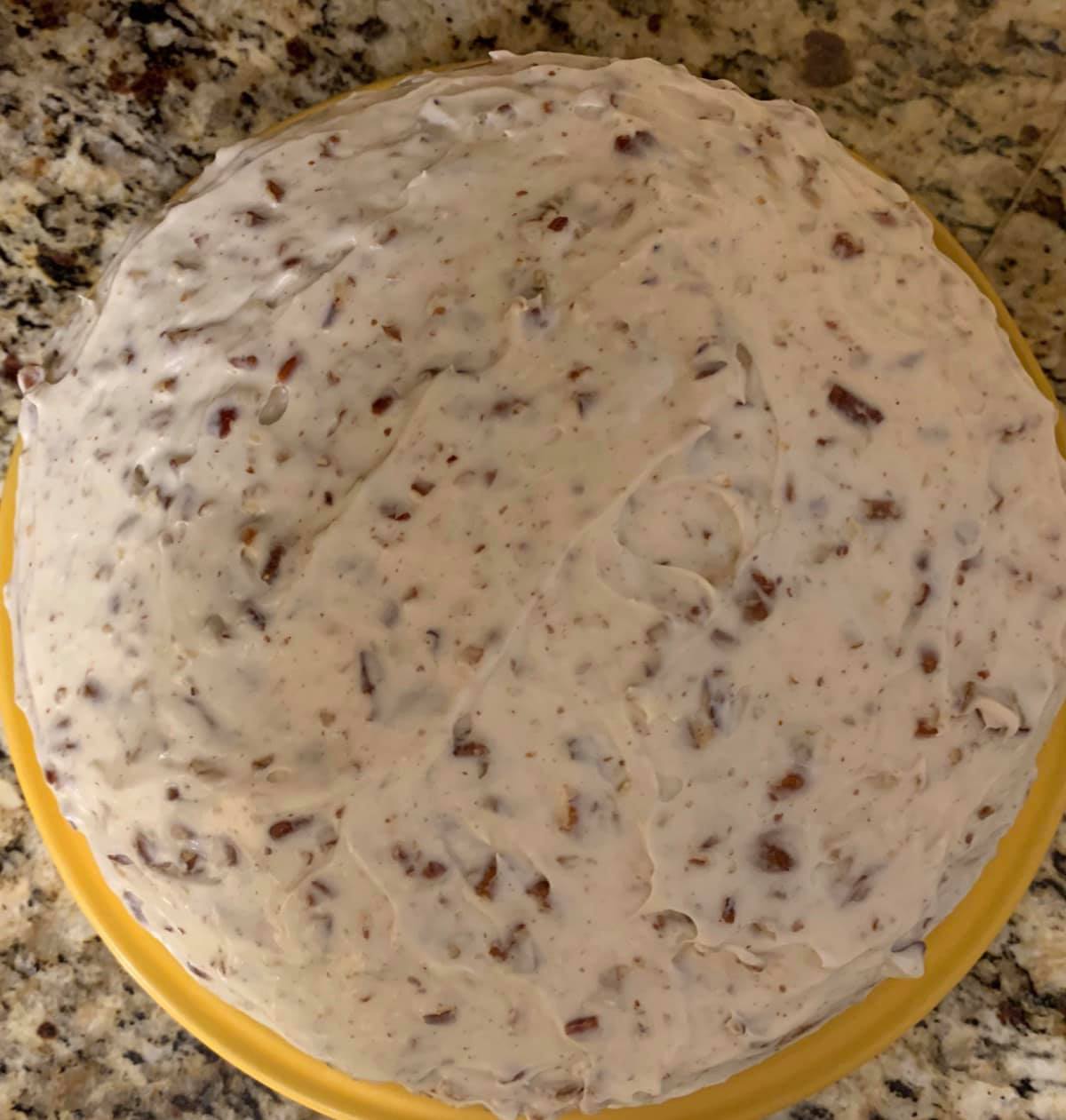 Cream cheese pecan frosting covering carrot cake